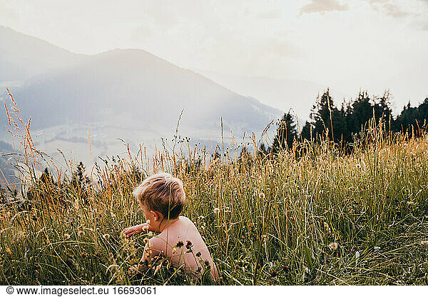 Young kid playing in the grass in the Alps in Austria