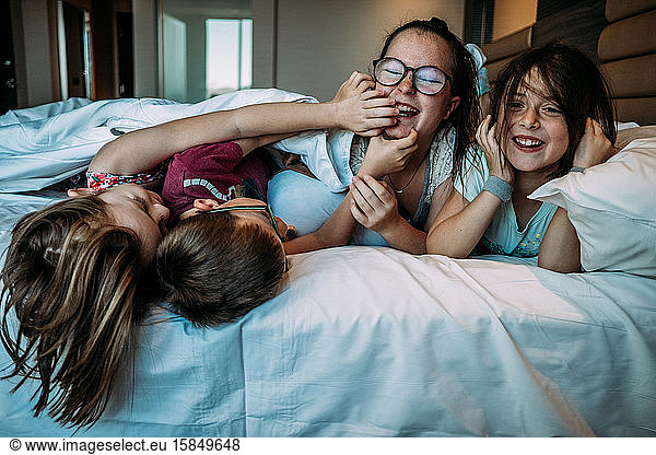 young kids playing on hotel bed while on vacation
