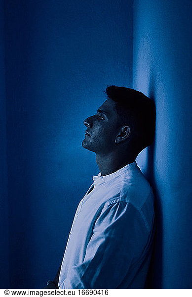 Young latin man thinking on a blue background