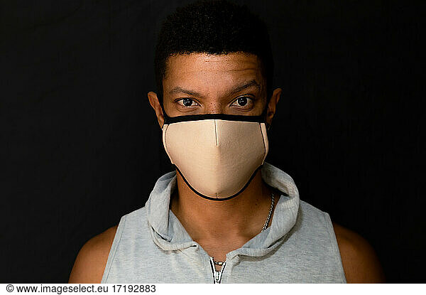 Young latin man with face mask and defiant look