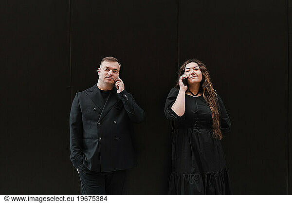 Young lovers woman and man in black clothes listen to audio message