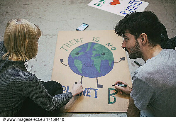 Young male and female protestor preparing poster for environmental issues