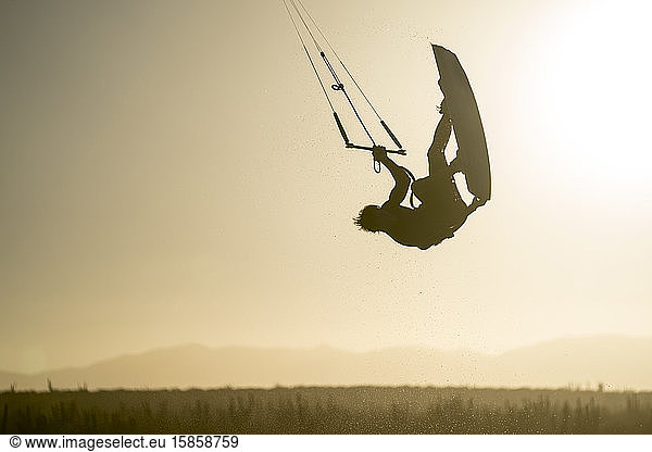 Young male athlete kiteboarding at sunset in La Ventana  Baja California  Mexico