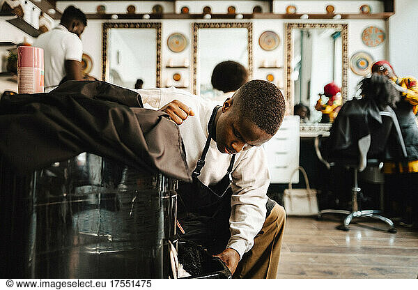 Young male barber opening drawer in hair salon