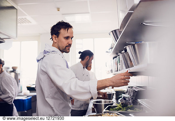 Young male chef reading order ticket in commercial kitchen