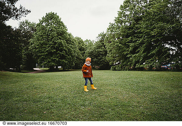 Young male child walking in the park on a cloudy day