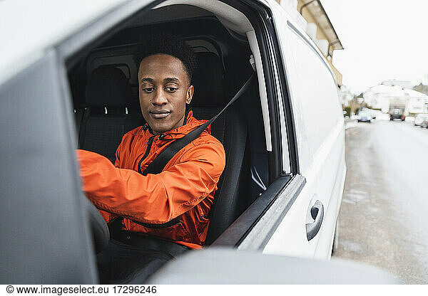 Young male driver driving delivery van