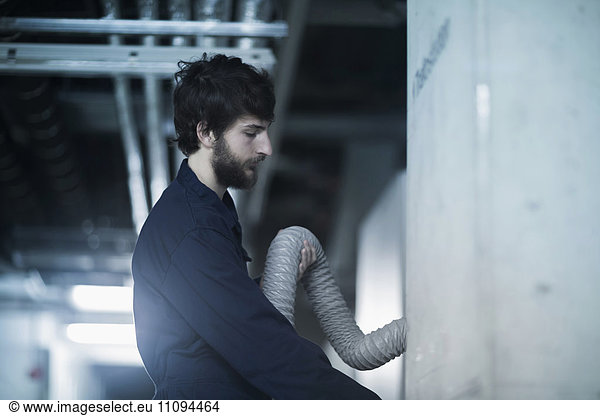 Young male engineer checking hose connection in an industrial plant