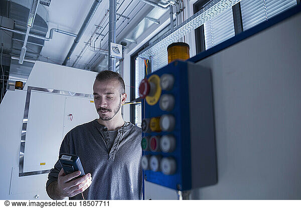 Young male engineer examining control panel with multimeter in an industrial plant  Freiburg im Breisgau  Baden-Württemberg  Germany