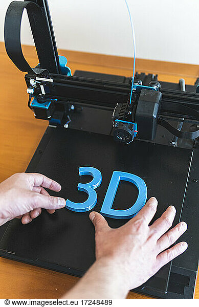 Young male engineer working on 3D printer machinery