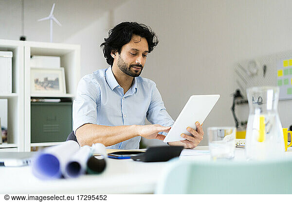 Young male entrepreneur using digital tablet while sitting at office