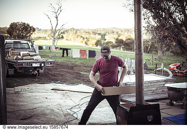 young male farmer with cap works on australian farm shed