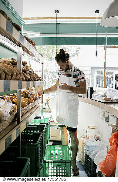 Young male owner arranging food in bakery