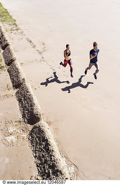 Young man and woman running along beach  elevated view