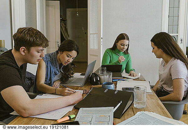 Young man and women doing homework at dining table