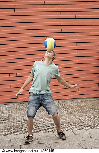 Young man balancing ball on forehead