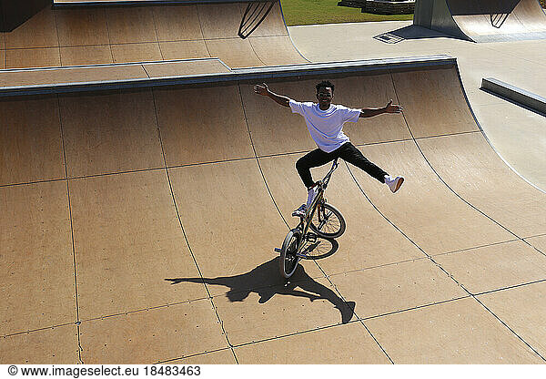 Young man balancing on BMX bike at skatepark
