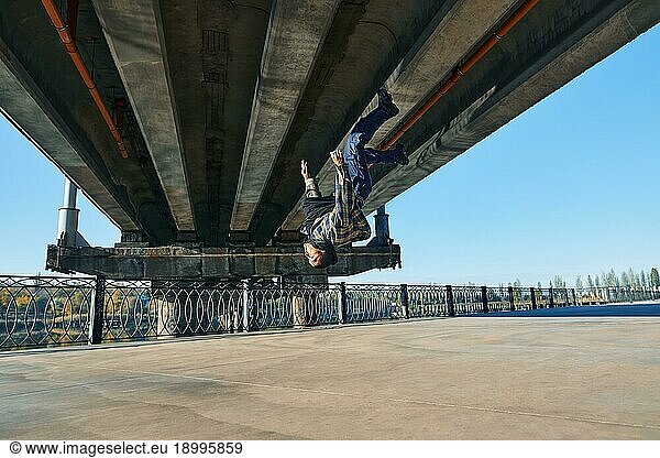 Young man break dancer doing somersault acrobatic stunts dancing on urban background. Street artist breakdancing outdoors