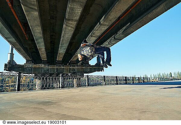 Young man break dancer doing somersault acrobatic stunts dancing on urban background. Street artist breakdancing outdoors