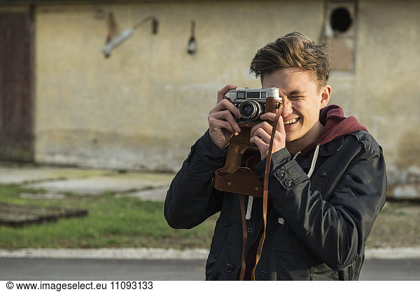 Young man clicking pictures with retro styled camera
