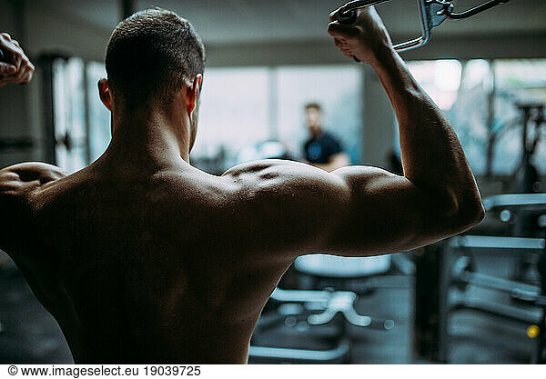 Young man doing chest exercise with cross machine.
