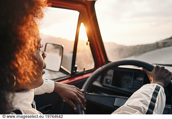 Young man driving van at sunset on vacation