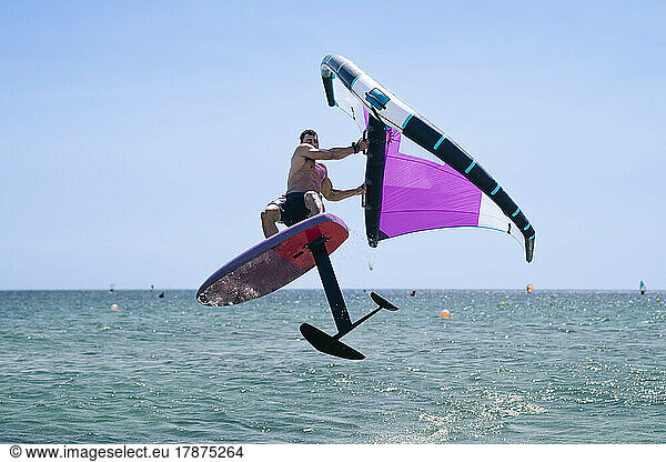 Young man enjoying hydrofoil in sea on sunny day