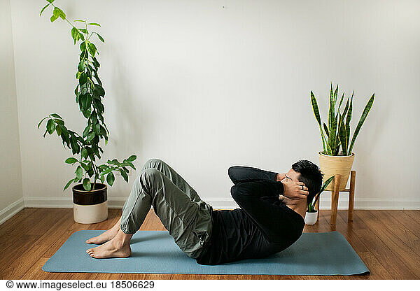 Young Man Exercising From Home on Yoga Mat near Plants