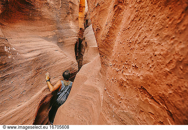 Young man exploring narrow slot canyons in Escalante  during summer