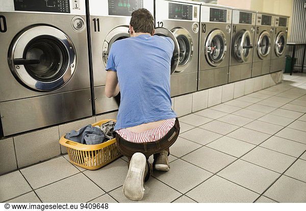Young man filling up cloths in machine