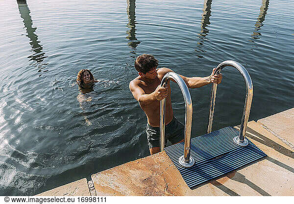 Young man getting out of the water onto a jetty
