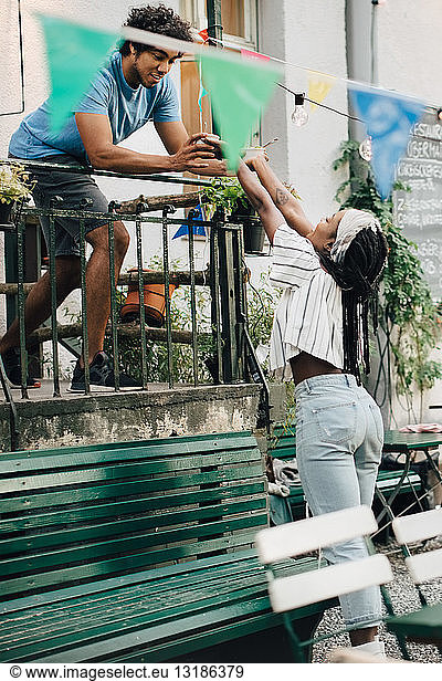 Young man giving food to female friend from balcony during garden party