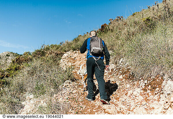 Young man hiking uphill in Malaga  Spain against blue sky
