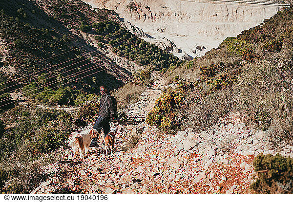 Young man hiking with two dogs in mountains in southern Spain  Malaga
