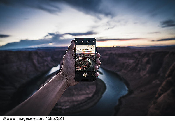 Young Man holding iPhone  photographing sunset at Horseshoe Bend