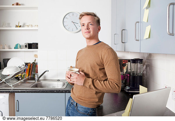Young man in kitchen with coffee cup