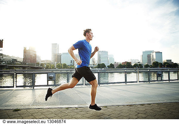 Young man jogging on promenade in city