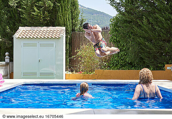 Young man jumping into a pool. Enjoy the holidays with the family.