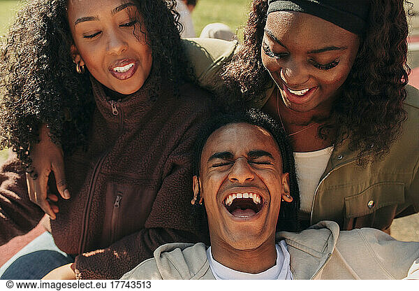 Young man laughing while leaning on female friends