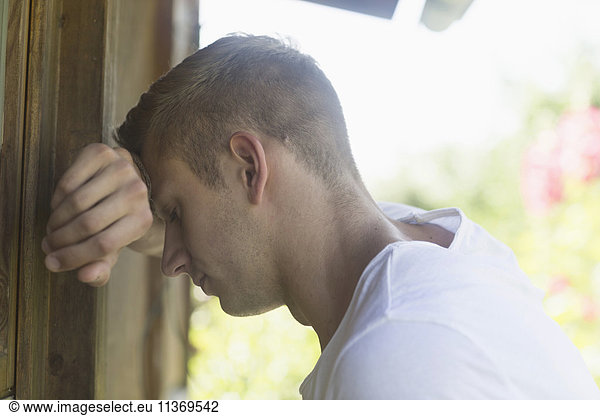 Young man leaning head to wall in sorrow
