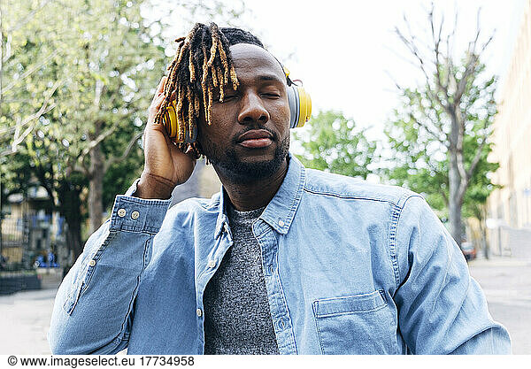 Young man listening music through wireless headphones
