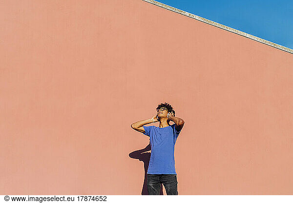 Young man listening music through wireless headphones on sunny day