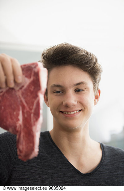 Young man looking at ham in kitchen