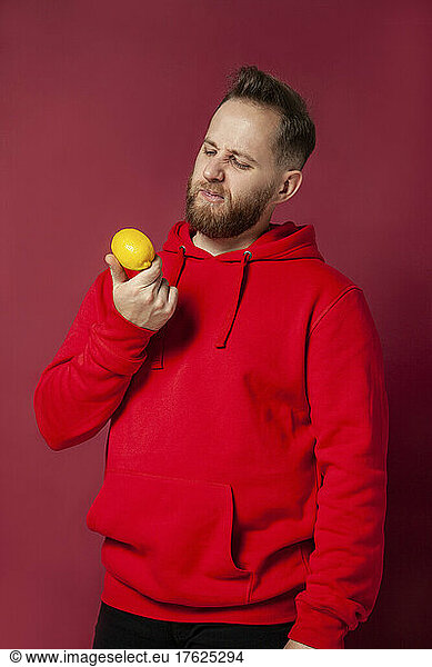 Young man looking at lemon in studio