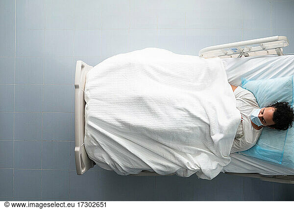 Young man lying asleep on a hospital bed. overhead photo.