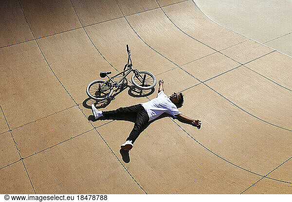 Young man lying down by BMX bike at skatepark