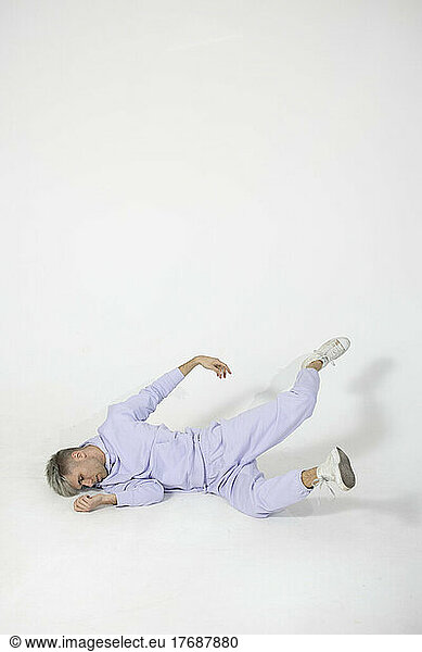 Young man lying on white floor