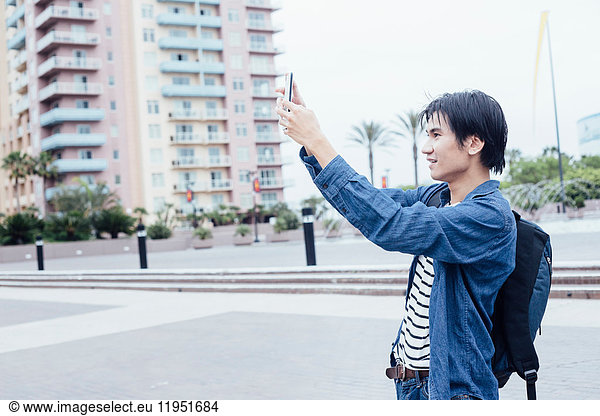 Young man outdoors  taking picture using smartphone
