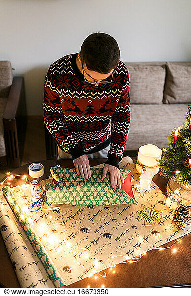 young man packs Christmas presents for friends and family