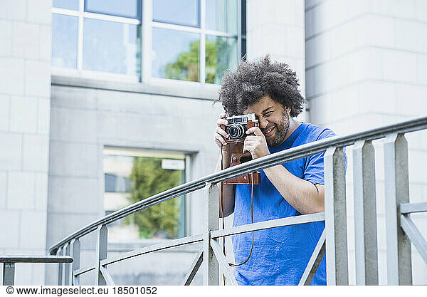 Young man photographing using retro style camera